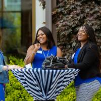 Three guests talking around a table outside.